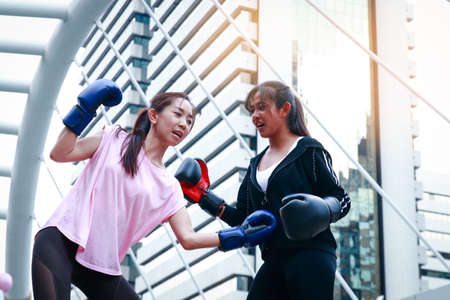 Two ladies put boxing glove on the back office building.の写真素材