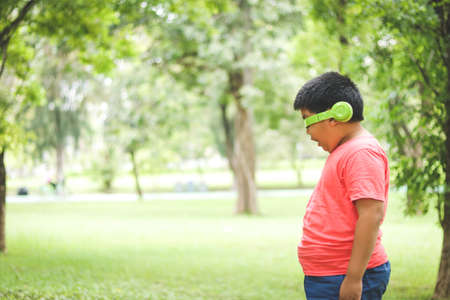 Boys wearing green music headphones Standing against the tree, closed eyes, happyの写真素材