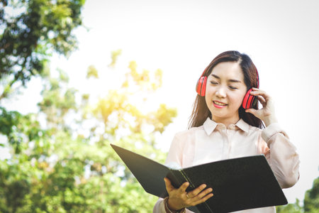 Beautiful women working in the office are reading data in document files while wearing headphones.の写真素材
