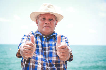 An elderly man, thumbs up, good health, come to the beach, relaxの写真素材