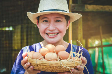 Young women do agricultural farms produce organic eggs. She smiled happy with the eggs in the basket.の写真素材