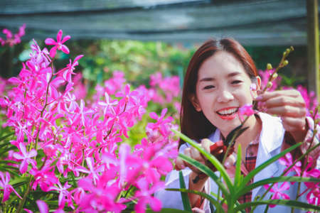 Women wearing white shirts, researchers use scissors to cut flowers to study, develop varieties.の写真素材