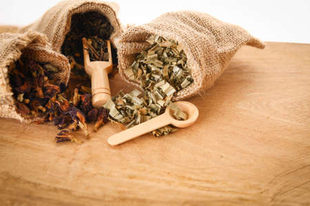Asian herbs are in brown sacks and wooden spoons placed on wooden floors. White backgroundの写真素材