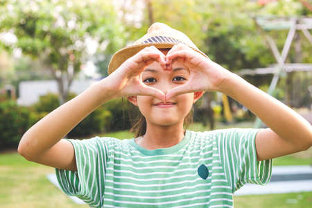 A cute Asian schoolgirl makes his hands a heart shape.の写真素材