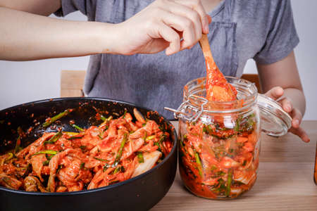 Asian woman sitting and making kimchi She is wearing protective gloves and a hat. To keep food clean. White background Korean fermented food concept made from vegetables.の写真素材