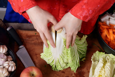 Korean women wear traditional red hanboks, make kimchi by tearing the Chinese cabbage. The concept of cooking fermented foods that are charming and fragrant, Asian cuisine from folk wisdomの写真素材