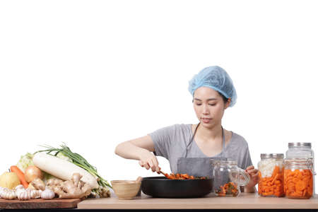 Asian woman sitting and making kimchi She is wearing protective gloves and a hat. To keep food clean. White background Korean fermented food concept made from vegetables. Clipping Path. isolatedの写真素材