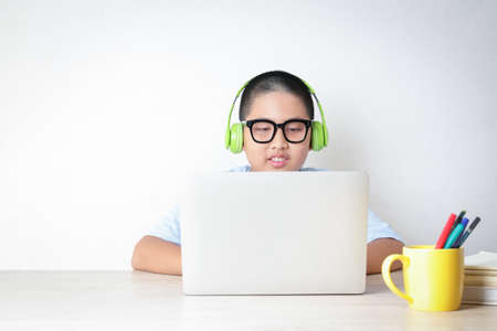 Asian male students learn online from home through video calls, using their laptop computers to communicate with their teachers. Social distance to reduce the spread of the coronavirus (COVID-19).の写真素材