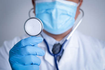 Doctors wearing masks and blue gloves. Hold a stethoscope to examine the patient. Medical care service concept, cure coronavirus. Copy spaceの写真素材