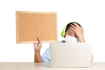 Asian boys learn online from home through video calls, using their laptop computers to communicate with their teachers. Hold a wooden sign for writing messages. Education concept Social distance.の写真素材