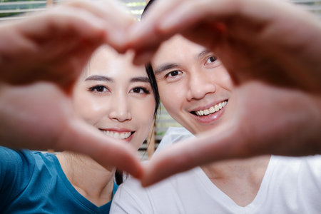 Asian couples make happy heart-shaped hands in their new home. The concept of married life starts a familyの写真素材