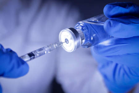 Doctors or scientists hold syringes and vials with the COVID-19 vaccine to try injections to treat patients in hospitals. Medical experiments prevent the spread of the coronavirusの写真素材