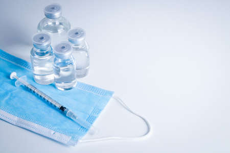 Anti-virus vaccine bottle with syringe and mask Placed on a white background Concept of vaccine for the coronavirus, or COVID-19. Hospital medical services. Copy spaceの写真素材