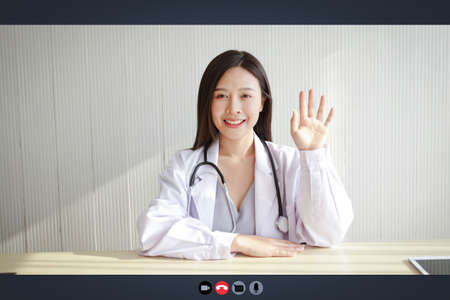Close-up on a computer screen, a beautiful Asian woman doctor treats a patient via online video call. Concept of medical service. Consult a sick person online During the coronavirus spreadの写真素材