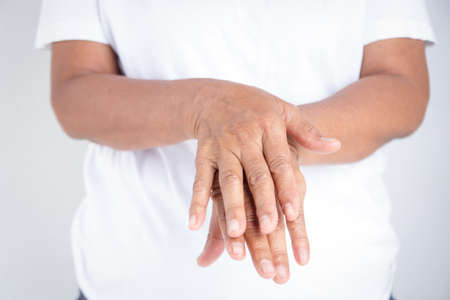 Elderly woman in white clothes wash their hands with alcohol gel. Prevent infection from the coronavirus. Concept of protection against COVID-19 virusの写真素材