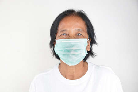 Elderly Asian women wear green masks to prevent the virus and dust. White background. The concept of healthcare for the elderlyの写真素材