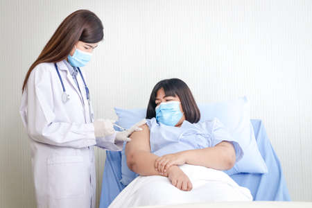 A female doctor injects an antiviral vaccine to a obese  woman patient.の写真素材