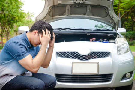Stressful Asian men raise their hands to hold their heads The car engine crashed while traveling, parked on the roadside waiting for help. Concept of car insuranceの写真素材