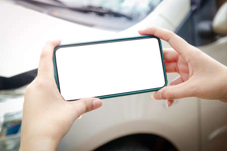 A woman holds a smartphone to take pictures of the area of â€‹â€‹a car crash in the...
