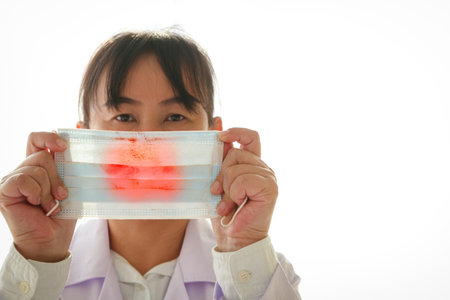 A female doctor was holding a mask with blood and virus marks.の写真素材