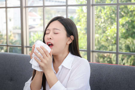 Beautiful woman long hair Asian sick Coughing or sneezing Cover your mouth and nose with tissue paper. Concept of health treatment Prevent transmission of virusの写真素材