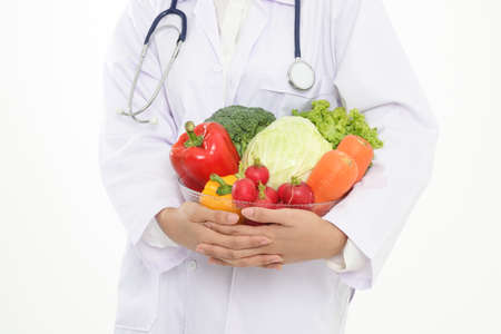 Doctor or nutritionist Holding a bowl of fresh organic vegetables Food for good health. Prescription food nutrition concept, healthy eating. White backgroundの写真素材