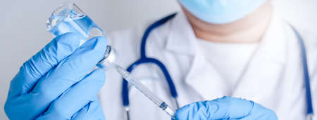 The male doctor carries a syringe and a vaccine vial to inject the patient to build immunity against viral infection. Concept of medical serviceの写真素材