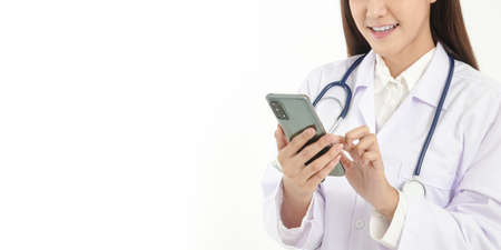 Smartphone concept Connect with online technology communications. A woman doctor holding a smartphone Chat online, treat patients through video calls. White background. Copy spaceの写真素材