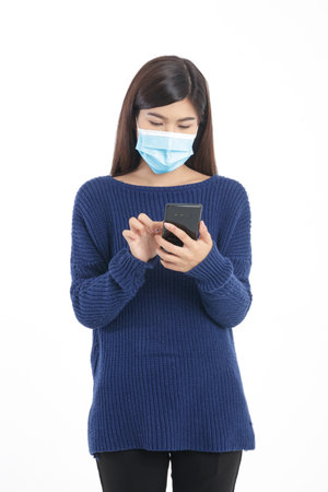 Asian woman wearing a mask Hold a black smartphone. Concept of communication, online conversation, social distancing. White background. isolatedの写真素材