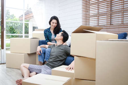 Asian couple moving into a new home Help unpack the brown paper box to decorate the house. Concept of starting a new life, building a family. Copy spaceの写真素材