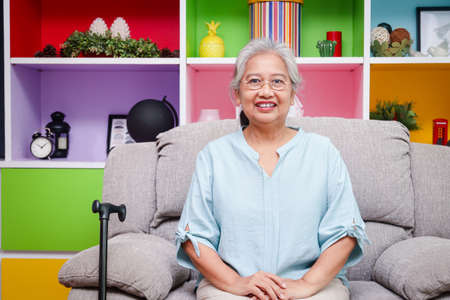 Asian elderly woman happy smile she is in good health Sit on the sofa in the house. concept of health care for the elderly in retirement age.の写真素材