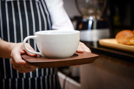 Hand made by a man holding a white coffee cup to send to customers. Coffee shop business concepts, entrepreneurs, doing business during the coronavirus pandemicの写真素材