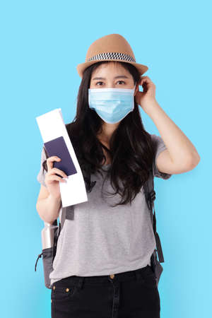 beautiful asian woman wear a mask and holding a passport to travel abroad Standing on a blue background. travel concept. Clipping Pathの写真素材