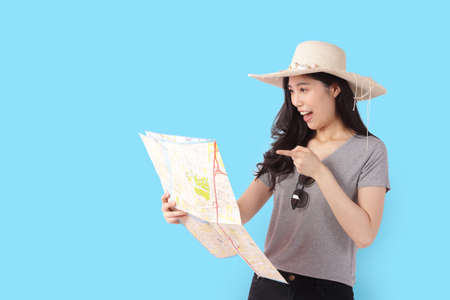 beautiful asian woman wearing a hat and holding a tourist map Standing on a blue background. travel concept. Clipping Pathの写真素材