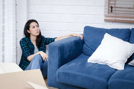 Stressed Asian woman moving things into a new home. Several large brown cardboard boxes were placed in the room. moving house conceptの写真素材