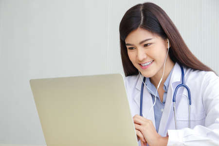 Asian female doctor online video call Check the symptoms with the patient via the Internet. on a...