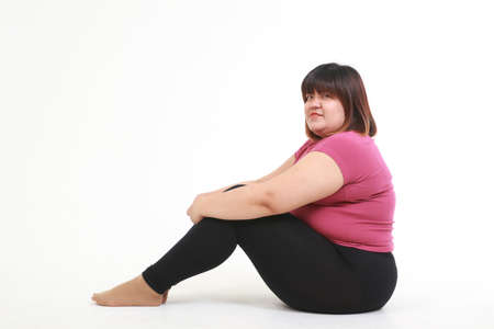 asian fat woman wear workout clothes sitting on a white background. health care concept, weight loss for good healthの写真素材