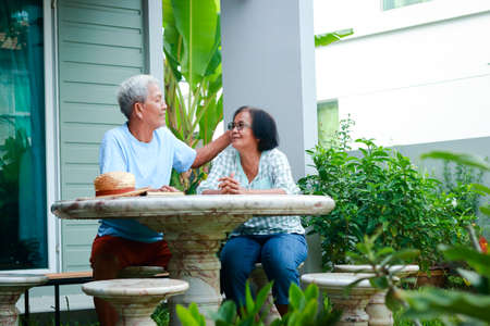 Asian elderly couple happy living at home sitting in the garden in front of the house Laugh, talk, have fun. concept of family Health care for the elderly in retirement.の写真素材