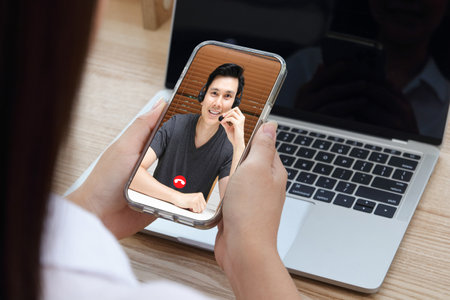 Asian woman working from home She is making an online video call on her smartphone to discuss work. concept of social distance modern communication technologyの写真素材