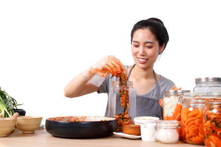 beautiful asian woman Sit and make kimchi, Korean fermented food. she wears protective gloves to maintain food cleanliness. White background. Korean fermented food concept made from vegetables.の写真素材