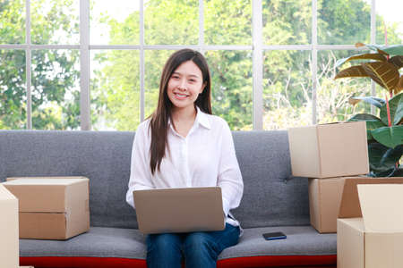 Asian beautiful woman entrepreneur Doing business online A happy smile sat on the sofa in the living room at home.の写真素材