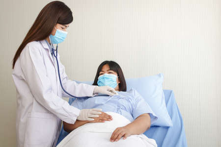 Asian female doctor use a stethoscope Check the heart rhythm of obese female patients. lying on the nursing bed. concept of medical services in hospitalsの写真素材