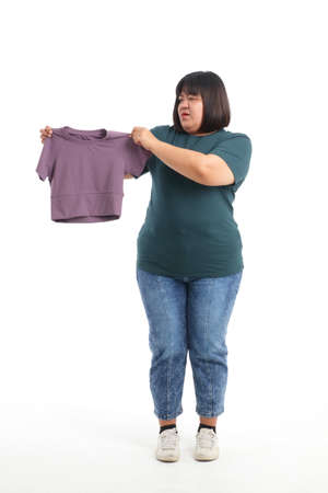 Fat Asian woman trying to lose weight She carries a small shirt that she can wear when she is thin. Weight loss concept. white backgroundの写真素材