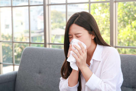 beautiful asian woman sick with the flu have a stuffy nose Hold a tissue to cover your mouth. Prevent the virus from spreading. health care conceptの写真素材