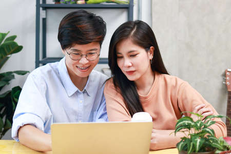 Lesbian couples spend time together at home watching media online on their laptops. Young same-sex married couples living together. Lesbian Couple Together Indoors Concept. LGBTの写真素材