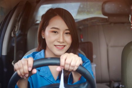 Beautiful Asian woman driving a car to work. She smiled happily. The concept of driving carefully in the rainy season in Thailandの写真素材
