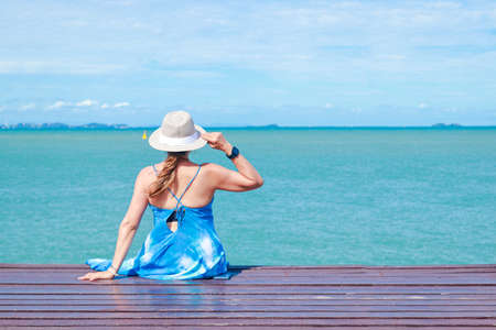 50 year old Asian woman sitting on a wooden floor by the sea Enjoyed the sea excursions during the holidays. Concept of natural tourism in Thailandの写真素材