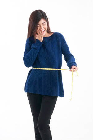 A beautiful, Asian woman. Use a tape measure around waist to check waist size. weight loss concept Taking care of your body to be beautiful and healthy. White background. isolatedの写真素材