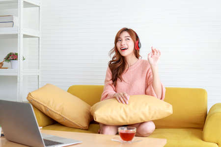 beautiful asian woman happy smile Sit at home listening to music in the living room. home isolation concept, social distance, work from homeの写真素材