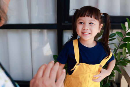 elderly grandmother with cute little granddaughter live at home together. Grandma dressed her granddaughter for school in the morning. educational concepts of kindergarten childrenの写真素材